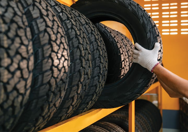 Someone takes a tyre off a rack of tyres. 